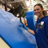 alumna smiling next to parade float